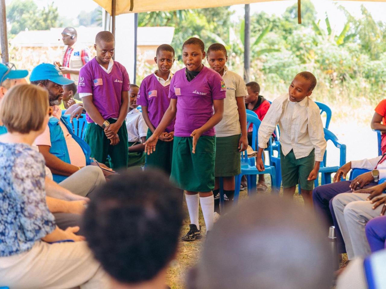Girls in purple tshirts speaking to seated audience